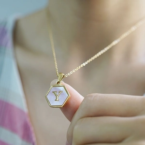 Macro shot of a hexagonal gold pendant with purple mother-of-pearl and letter Y