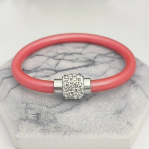Nahaufnahme von korallenrosa Silikonarmband mit silbernem Zylinder und Pavé-Strasssteinen