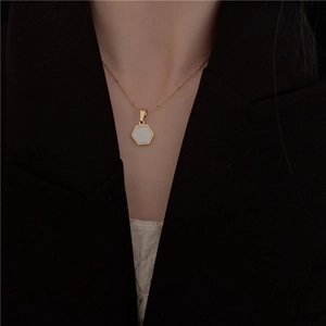 Detail of a gold-plated hexagon mother-of-pearl pendant necklace on a model