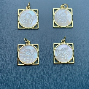 Macro view of square gold pendants with white shell inlay featuring angel carvings