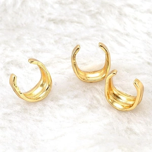 Detailed view of three 18K gold plated stainless steel C-shaped ear cuffs on white plush