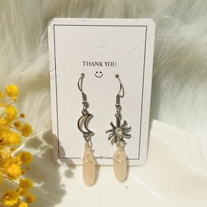 Detailed close-up of handmade wire-wrapped crystal earrings with moon and sun charms