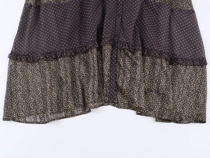 Detail of dark brown polka dot fabric with ruffles and buttons on a bohemian dress