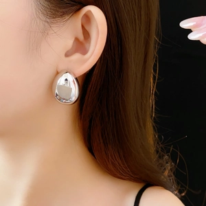Gros plan sur une boucle d'oreille goutte en argent poli avec une finition métallique