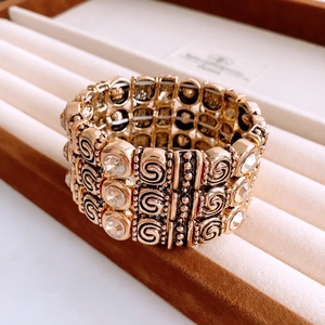 Close-up of vintage gold elastic bracelet with spiral texture and sparkling crystals
