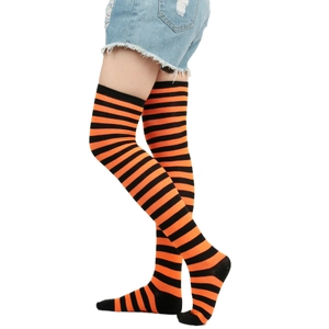 Close-up of orange and black striped over-knee high socks in soft knitted cotton fabric