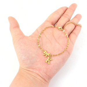 Macro view of gold bow bracelet featuring a K letter pendant with lobster clasp and chain