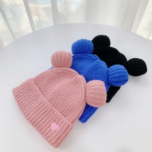 Detailed close-up of knitted beanies with bear ears in pink, blue, and black colors