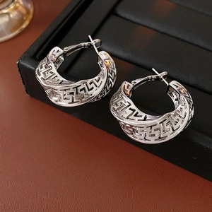 Detailed macro view of silver hollow geometric pattern on elegant twist hoop earrings