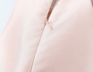 Détail du dos de la robe en satin rose montrant le tissu lisse et la fermeture éclair invisible