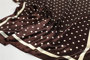 Detailed view of dark brown silk scarf with white polka dots and elegant satin texture