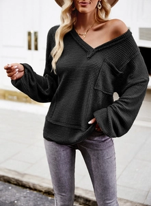 Close-up of black waffle knit texture on V-neck long sleeve top with pocket detail