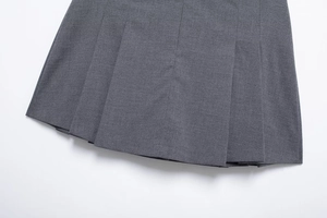 Close-up of the pleated hem and fabric texture on a dark grey low-waist mini skirt