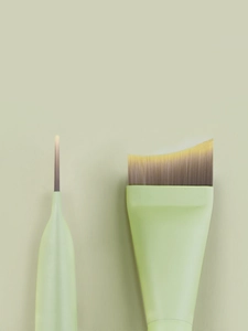 Detail of light green thin angled foundation brush and fan mask brush with matte handle