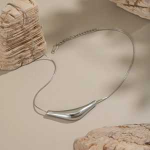 Détail du pendentif argenté en forme de bateau sur fond de pierre naturelle texturée