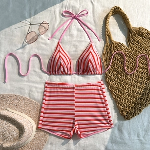 Flat lay of a red and pink striped high-waisted bikini set with vacation accessories
