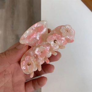 Detailed macro of a pink marble acetate hair claw clip with gold rhinestone flowers