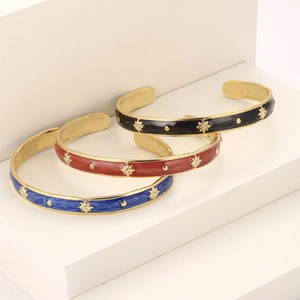 Three gold-plated C-shaped enamel bangles with star patterns and small rhinestones
