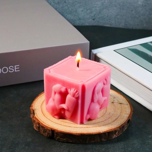 Bougie rose parfumée avec relief de lapin et carotte sur un socle en bois rustique