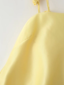 Detail of yellow satin dress featuring delicate thin straps and shoulder knot design