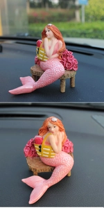Detail of mermaid car ornament with pink gradient tail on a dashboard bench