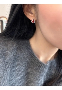 Detail view of red gourd earring with white diamonds on model wearing grey knitwear