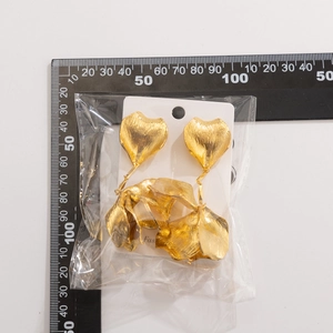 Detail of gold petal earrings with a brushed metal finish and stacked heart-shaped leaves