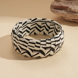 Detail shot of wide zebra print bracelet with woven leather texture on a neutral stone base