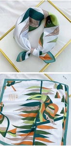 Close-up of a satin silk scarf featuring tropical leaves and toucan print details