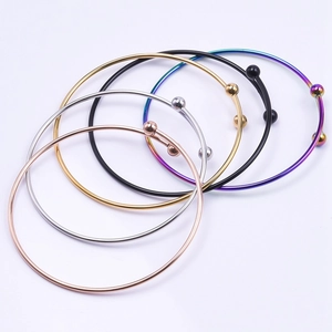 Detail showing five colors of slim stainless steel open bangles with metal spheres