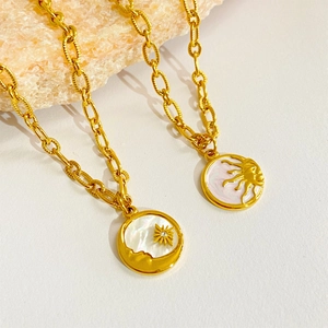 Vintage 18k gold plated sun and moon coin necklaces on a pink stone background