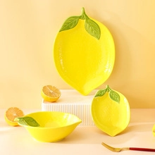 Detailed view of high-quality lemon-shaped ceramic plates and bowl in bright yellow finish