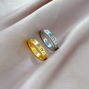 Macro detail of gold and silver Roman numeral rings with zircon stones on silk