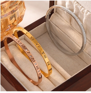 Detailed view of roman numeral engraved bangles with zircons in a wooden jewelry box