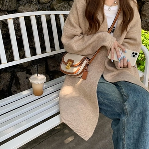Dettaglio di una borsa a sella bicolore marrone e beige con fibbia dorata e look casual