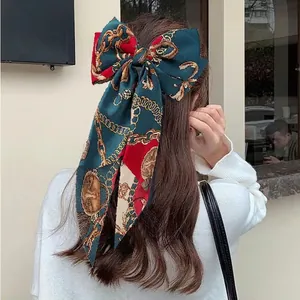 Elegant oversized satin bow hair clip with vintage chain print on model's long hair