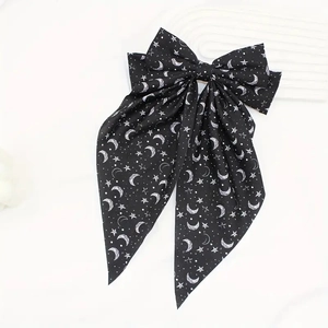 Detail of long black bow hair clip with white star and crescent moon patterns
