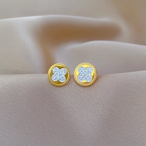 Macro shot of titanium steel gold clover earrings with white crystals on silk