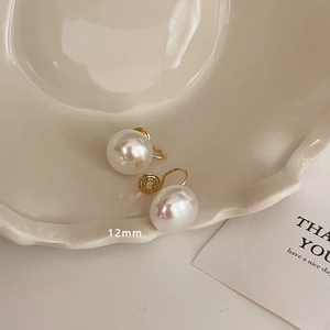 Close-up of 12mm white pearl earrings with gold-tone spiral clip-on fasteners