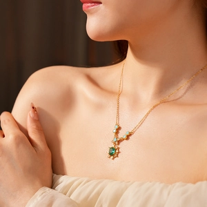 Détail du collier vintage doré avec pierres vert émeraude et accents de zircon sur modèle