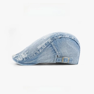 Close-up of light blue washed denim beret with distressed texture and metal buckle