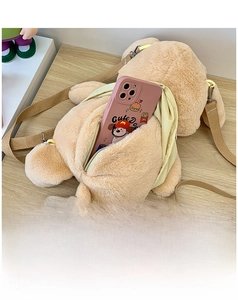 Detail of plush poodle backpack showing back zipper opening and internal phone storage