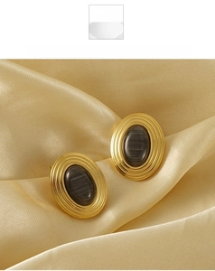 Detailed shot of 18K gold stainless steel earrings with grey oval gemstone on silk