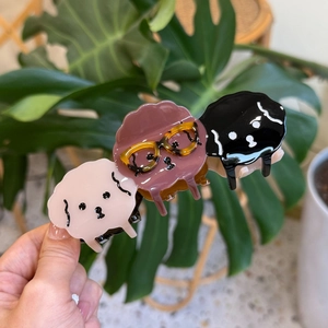 Three cute acetate puppy hair claws in pink, brown and black colors held in hand