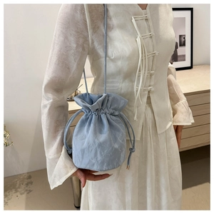 Close-up of light blue drawstring bucket bag with wrinkled texture on a model