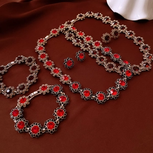 Detailed view of luxury gold jewelry set with red floral crystal patterns on fabric