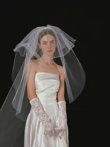 Detailed view of elegant white satin wedding dress with layered tulle veil and lace gloves