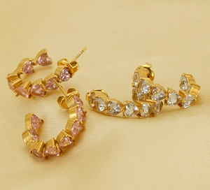 Detailed close-up of U-shaped gold earrings with pink and white heart-cut cubic zirconia