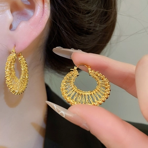 Detail of 18k gold plated woven hollow hoop earrings showing intricate braided metal texture