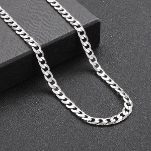 Macro detail of polished silver cuban link chain against black background